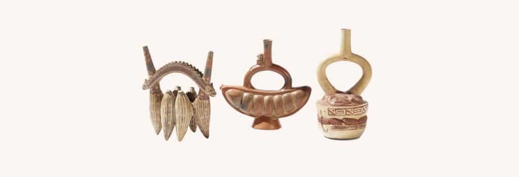 Three ancient pottery vessels with curved handles and decorative motifs placed side by side on a light background, museum-style display.
